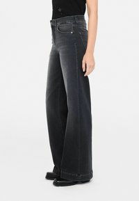 Zwarte jeans met wijde pijpen en een hoge taille, gemaakt van denim. Bevat voorzakken, een knoop- en ritsluiting, en een nette zoom.