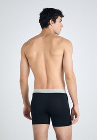 Fekete boxernadrág szürke Calvin Klein logós derékrésszel, sima anyagból készült, testhezálló kivitelben.