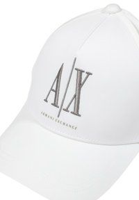 Gorra de béisbol blanca con un logo elevado en gris "A/X" y el texto "ARMANI EXCHANGE". El diseño incluye una tela estructurada y suave, además de acentos cosidos.