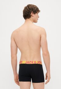 Černé boxerky s širokým žlutým páskem s růžovým nápisem "JACK & JONES", hladká tkanina a přiléhavý střih.