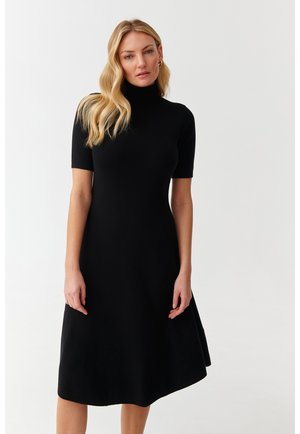 Abito nero in maglia con collo alto e maniche corte, caratterizzato da una gonna ampia e una texture liscia. Design semplice senza motivi.