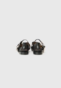 Schwarze Ledersandalen mit glatter Textur, offener Ferse, dünnen Riemen und runden Zehen, ausgestattet mit einem kleinen Absatz und einer verstellbaren Schnalle.