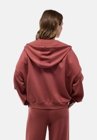 Sweatshirt surdimensionné à capuche de couleur rose doux, fabriqué en tissu doux, doté de manches longues et d'un ourlet côtelé.