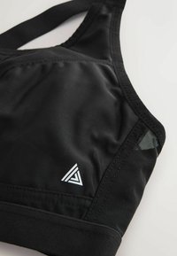 Schwarzer Sport-BH aus glattem Material mit Mesh-Akzenten. Verfügt über ein dreieckiges Logo und verstellbare Träger für Komfort und Unterstützung.