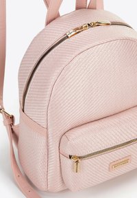 Růžový syntetický kožený batoh s texturovaným povrchem, dvěma předními kapsami na zip, zlatým kováním a nastavitelnými ramenními popruhy.