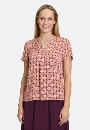 Korte mouwen blouse van een gemêleerde stof met een roze basis en geometrische ontwerpen in gele, rode en oranje tinten; v-hals en een losse pasvorm.