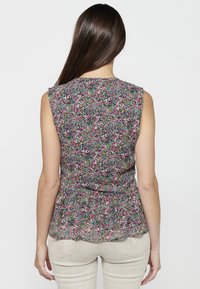 Top peplum floreale con maniche a cappuccio, caratterizzato da un motivo multicolore di fiori rosa, blu e verdi su uno sfondo scuro.