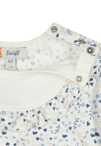 Indumento bianco con stampa floreale in tonalità di blu e rosa. Presenta un collo con volant e chiusure a pressione per un facile vestire. Etichetta della taglia visibile.