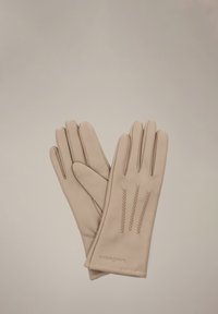 Beżowe skórzane rękawiczki z trzema dekoracyjnymi przeszyciami z tyłu. Charakteryzują się gładką fakturą i dopasowanym krojem.