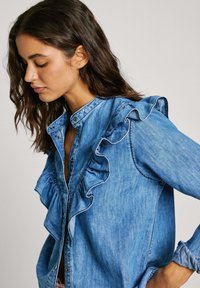 Denim srajca na gumb z nabranim oblikovanjem po sprednji strani in rokavih, v svetlo modri barvi in teksturiranem materialu.