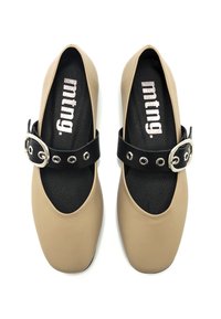 Scarpe beige slip-on con punta arrotondata, soletta nera testurizzata e una fascetta nera con una fibbia argentata e occhielli.