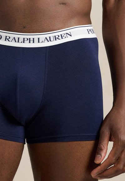 Μποξεράκια σε ναυτικό μπλε με λευκή ζώνη μέσης που φέρει το λογότυπο "Polo Ralph Lauren" σε ναυτικό μπλε κείμενο, κατασκευασμένα από λείο ελαστικό ύφασμα.