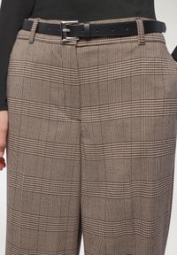 Pantaloni a scacchi in tonalità di marrone e beige, con un tessuto testurizzato, pieghe e una cintura nera con fibbia in argento.