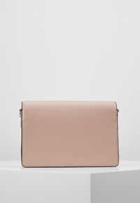 Prostokątna torebka kopertówka w kolorze różowym z klapą, z delikatnym czarnym wykończeniem i metalowymi elementami po bokach, wystawiona na białym postumencie.