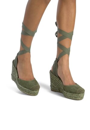 Sandales compensées en daim vert avec détail en jute tressé, brides de cheville et bout rond. Le talon mesure environ 7,5 cm.