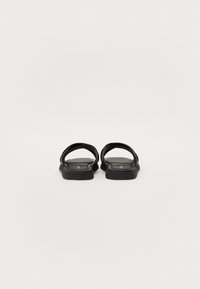 Svarte sandaler med flatt såle, med to brede stropper. Materialet ser jevnt ut med en svak glans. Enkel og strømlinjeformet design.