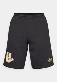 Černé sportovní šortky z měkké tkaniny, se zlatým logem Adidas a grafikou "MANITED". Elastický pas s šňůrkou pro úpravu velikosti.
