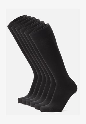 Calzini neri di cotone al ginocchio esposti in fila, caratterizzati da una texture liscia, punte rinforzate e un bordo a coste nella parte superiore.