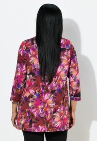 Bluzka z długim rękawem z żywym kwiatowym wzorem w odcieniach różu, fioletu i pomarańczy. Wykonana z gładkiego, lekkiego materiału.