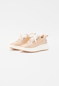 Beige plattform sneakers med teksturert overdel, hvite sømdetaljer og hvite snørebåndslukkinger. Har en tykk hvit såle med en taggete såle.