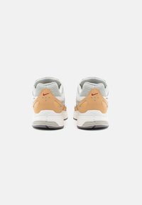 Γκρι και μπεζ αθλητικό παπούτσι με δομημένο σχέδιο, με υφασμένα στοιχεία στη φτέρνα, μαλακή σόλα και κόκκινη λεπτομέρεια λογότυπου στο πίσω μέρος.