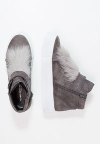 Baskets montantes en cuir suédé gris avec semelles en caoutchouc blanc, présentant des accents en fourrure grise et une fermeture éclair. Texture lisse avec un design élégant et moderne.