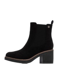 Stivale alla caviglia in suede nero con pannello laterale elastico testurizzato, punta arrotondata e tacco a blocco chunky. Presenta una cucitura a contrasto lungo la suola.