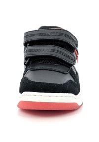 Zapatilla deportiva negra y roja con correas de velcro, materiales en ante texturizado y sintético liso, suela de goma blanca con fondo rojo.