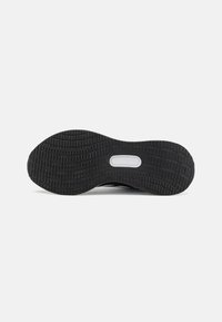 Black rubber outsole with textured traction pattern, featuring a central cutout for cushioning. Smooth edge and rounded toe design.