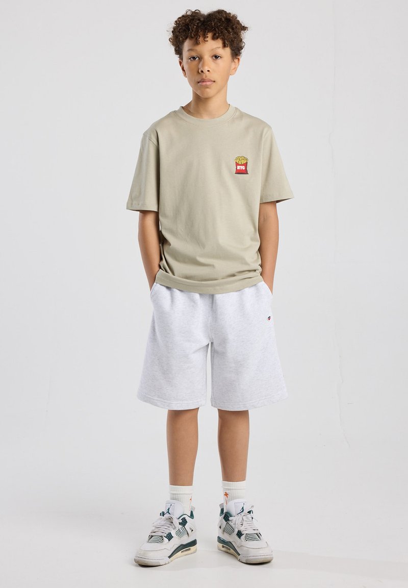 Light gray t-shirt with a small french fries logo, paired with white sweat shorts. Accessories include patterned socks and sneakers.