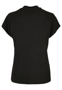 T-shirt en coton noir avec un col montant, des manches courtes et une coupe ample. Texture lisse et fentes sur les côtés à l'ourlet pour faciliter les mouvements.