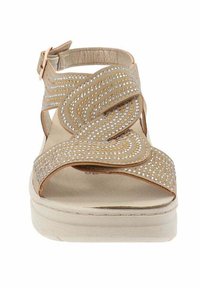 Sandal beige con cinturini incrociati caratterizzati da piccoli strass, un sottopiede imbottito e una suola spessa e leggera. Cinturino alla caviglia regolabile.