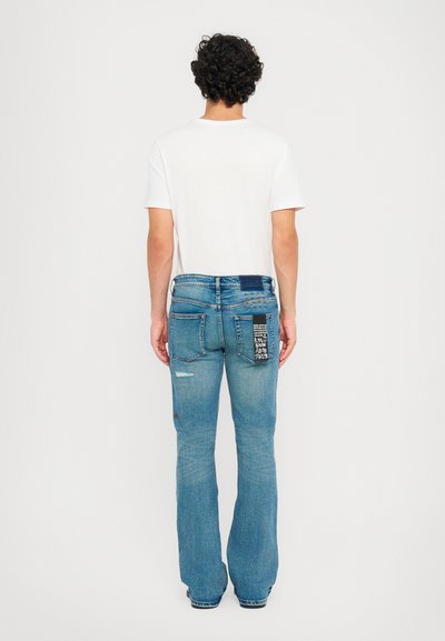 Μπλε τζιν παντελόνι με καμπάνα, με φθαρμένο σχέδιο, λεπτομέρειες από ύφασμα και πέντε τσέπες. Κανονικός ζωνάκος με θηλιές για ζώνη.