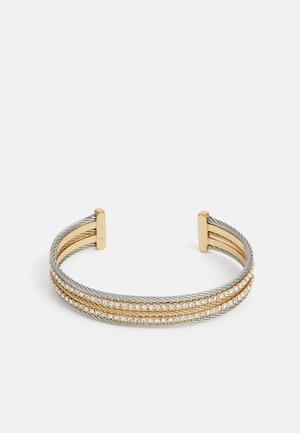 Cuff bracelet featuring intertwined silver and gold metal, embellished with a row of clear gemstones along the center. Smooth texture, open design.