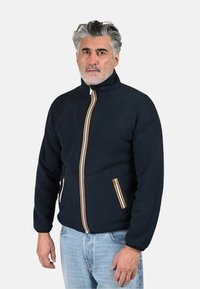 Giacca in pile blu navy con collo alto, dotata di una zip frontale a strisce multiple e tasche laterali con strisce decorative. Adatta per un abbigliamento casual.