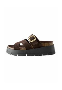 Sandale slip-on din suede maro cu talpă din cauciuc negru, având bretele încrucișate și un accent cu cataramă aurie, finisate cu o talpă intermediară asemănătoare cu plută.