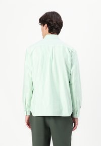 Green and white striped shirt with a button-down collar, long sleeves, and a relaxed fit. Features a back yoke and subtle textured fabric.