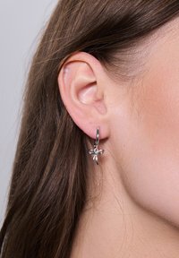 Srebrne kolczyki w kształcie obręczy z delikatnym wzorem ważki. Ważka ozdobiona subtelną fakturą oraz refleksyjnymi powierzchniami.