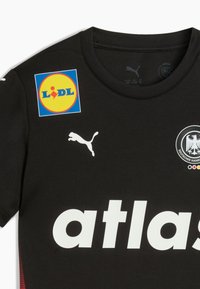Must mustre ja valgete tähtedega "atlas" ning Puma logo. Sisaldab Lidl-i värvilist logo ja ümmargust märki kotkaga.