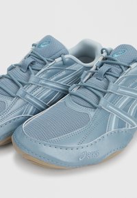Ανοιχτού μπλε αθλητικά παπούτσια Asics με πλέγμα και συνθετικές επικαλύψεις, κλείσιμο με κορδόνια και μπεζ λαστιχένιες σόλες, εμφανιζόμενα από κοντινή μπροστινή γωνία.