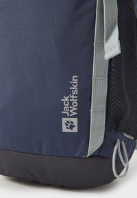 Tamsiai mėlyna kuprinė, pagaminta iš tekstūruoto audinio, su pilku logotipu, tinkleliu užtrauktuku ir pilkomis detalėmis. Apatinė dalis tamsesnio atspalvio.