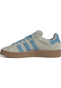 Szürke velúr sneaker világoskék díszítésekkel és fűzőkkel. Az oldalon három vízszintes csík található, és barna gumitalppal rendelkezik.