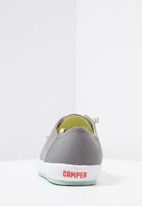 Baskets en toile grises avec une surface texturée, semelle vert menthe et doublure intérieure jaune. Présente un logo rouge "CAMPER" sur le talon.