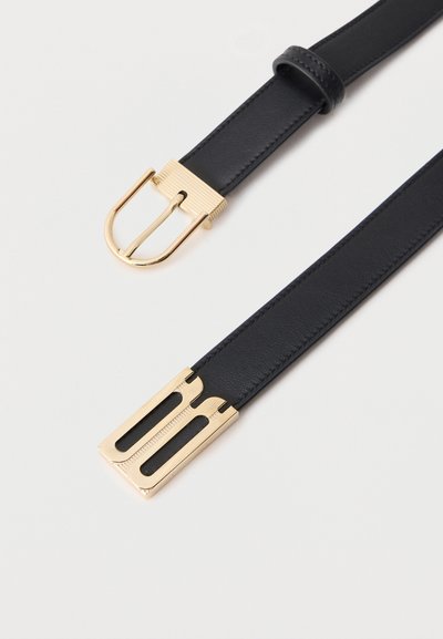 Μαύρη δερμάτινη ζώνη με χρυσή αγκράφα σε σχήμα D στη μία άκρη και αντίστοιχη χρυσή ορθογώνια άκρη στην άλλη, τοποθετημένη επίπεδα σε λευκό φόντο.