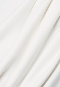 Weicher, weißer Stoff mit subtilen Falten und einer glatten Textur, die sanfte Schatten und eine saubere, helle Oberfläche zeigt.