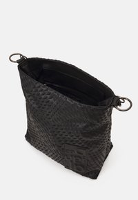 Schwarze Tasche aus strukturiertem Material mit einem Rautenmuster. Verfügt über eine Logo-Plakette und silberne Ringbeschläge zum Tragen. Offenes Oberteil-Design.