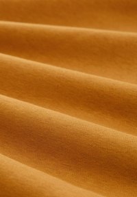 Un material textil moale, cu textură, de culoare galben muștar cald, care evidențiază plieri netede și un model de țesătură uniform. Potrivit pentru diverse aplicații.