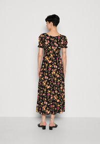 Svart blommig klänning med puffärmar, med blommönster i gult, rosa och vitt, samt en knälång A-linjeformad silhuett.
