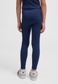Mörkblå ribbade leggings med en tight passform, med hög midja och matchade med vita sneakers med färgade detaljer och en logotyp.
