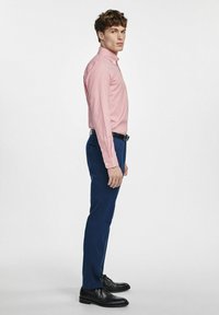 Czerwona i biała koszula w kratę z kołnierzykiem zapinanym na guziki, w zestawie ze slim-fit granatowymi spodniami i czarnymi butami eleganckimi.